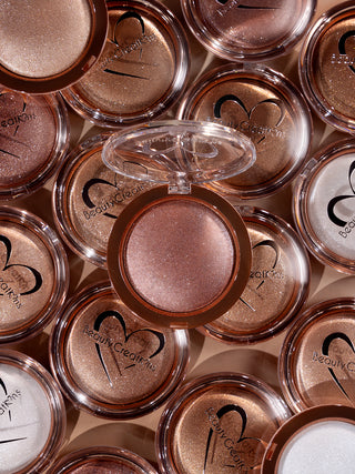 a collage of Shimmer veil body and face highlighter compact cases with Beauty Creations logo on a gold background