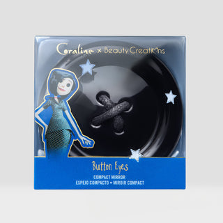 Coraline x Beauty Creations 'Button Eyes' compact mirror in its original retail packaging, featuring a large black button with dark gray eyes on a blue and black box with an illustration of Other Mother.