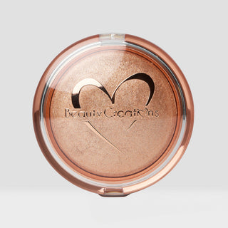 Compact powder with 'Beauti Creations' branding on a light gray background. Shade is Champagne Kiss Face and Body highlighter.