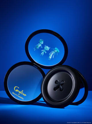 Three round black compact-style containers arranged together on a blue studio background. One compact lid shows a ghost scene, another shows the brand name Coraline in yellow, and the front compact has a large button detail.