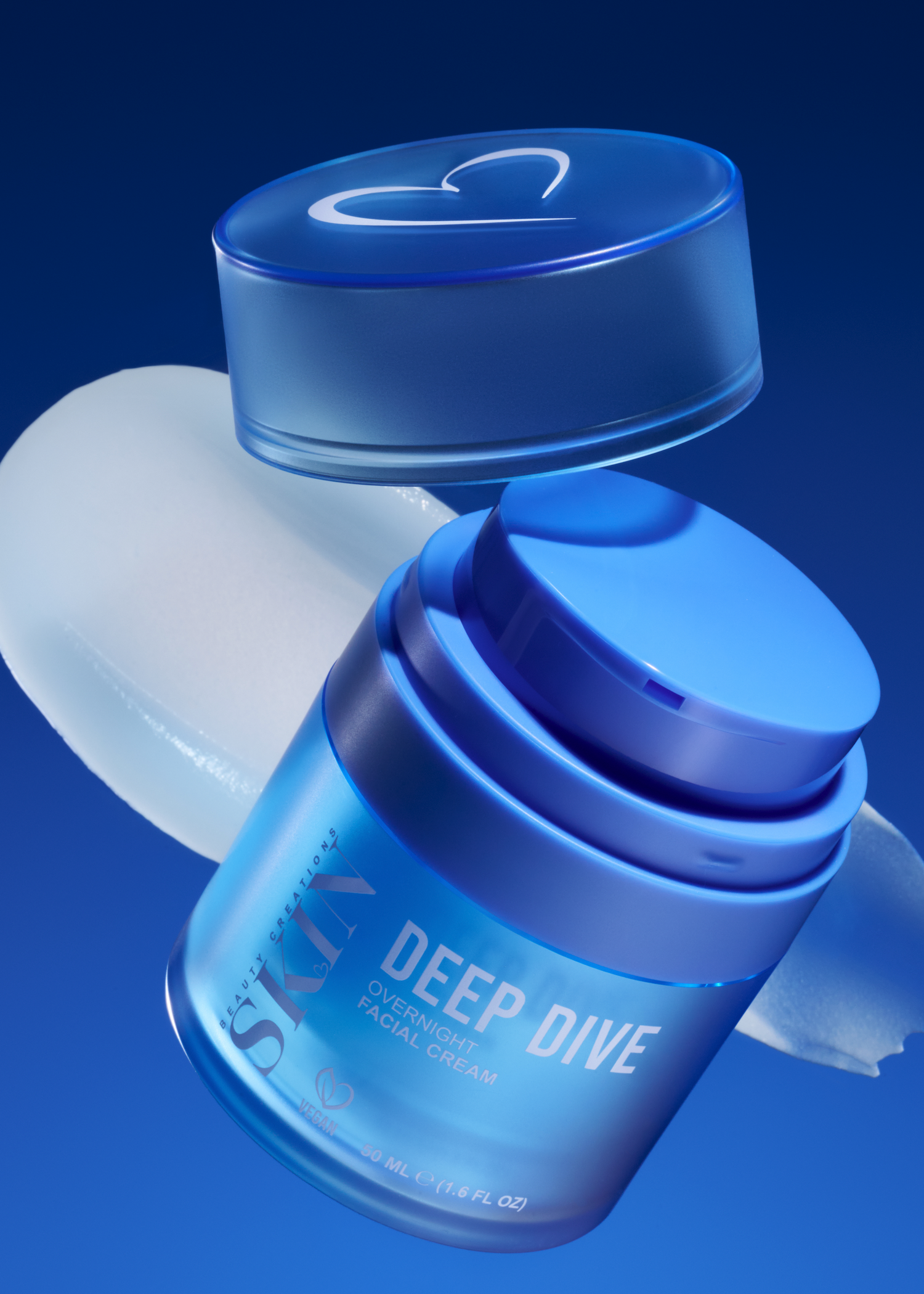 A blue cosmetic jar labeled 'SKIN DEEP DIVE' with its matching cap floating above, set against a dark blue gradient background with a white cream smear behind it.