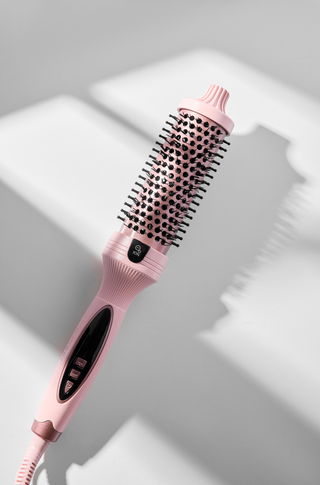Pink hairbrush with black bristle head on a light gray background