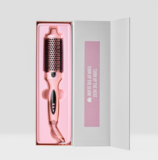 Rose gold hairbrush in a decorative box with text on a light gray background